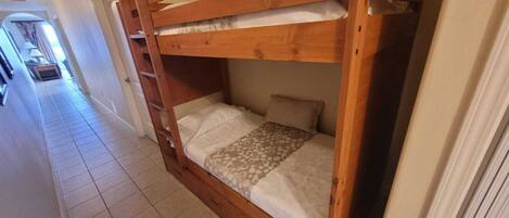 A bunk bed with a ladder, a patterned bedspread, and a pillow.
