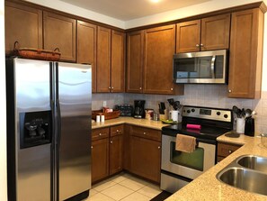 Fully equipped kitchen with refrigerator, microwave, stove, and sink.