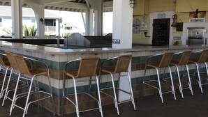 Et udendørs barområde med grill, siddepladser og et skilt, der angiver røgfri zone.