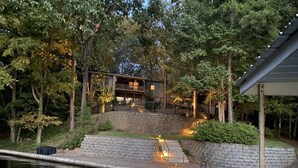 Une propriété au bord du lac, dotée d’un mur de soutènement en pierre, d’une terrasse en bois et d’un bâtiment avec un balcon.