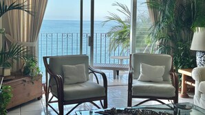 A room with two armchairs, a glass coffee table, and a view of the sea through a large sliding glass door. - Beautiful Condo in Playas Gemelas, Puerto Vallarta (Puerto Vallarta)