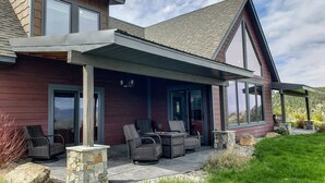 A modern house with a covered patio, stone pillars, and outdoor furniture.