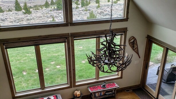 A spacious living room with large windows offering a view of a mountainous landscape.