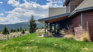 A modern house with a covered porch, a stone pathway, and a view of mountains.