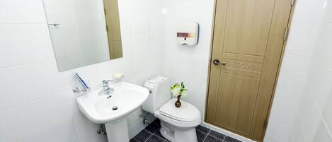A bathroom with a white sink, toilet, and a wooden door.