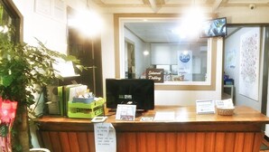 Un comptoir d’accueil en bois, un téléviseur fixé au mur et un panneau indiquant que l’endroit est réservé aux voyageurs musulmans.