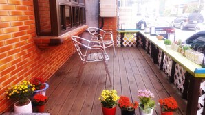 Une terrasse en bois avec des chaises en métal, des plantes en pot et une table.