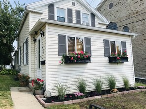 A two-story house with white siding and dark shutters, featuring flower boxes on the windows and a brick pathway leading to the door. - Walk to Downtown - 10 Mins to Starved Rock! (Lasalle)