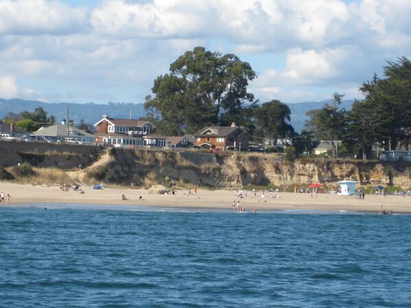 A beach with houses and a cliff.