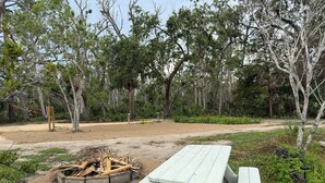 A picnic table and fire pit in a wooded area.