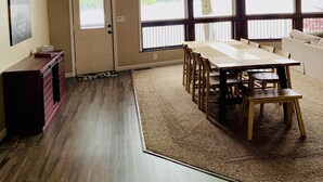 Ein geräumiger Raum mit hohen Decken, großen Fenstern, einem Esstisch und einer gemütlichen Sitzecke.