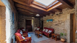 A cozy room with stone walls, wooden furniture, and a skylight.