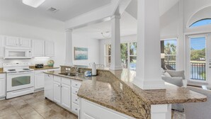 A spacious kitchen with white cabinetry, a granite countertop, and a large window offering a view of the outdoors. - Pet Friendly ~ Community Pool (Miramar Beach)