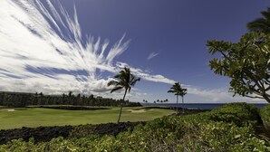 En golfbana med fri utsikt över havet och ett hotell i bakgrunden.