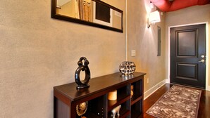 Un couloir avec une console en bois, un miroir et une porte.