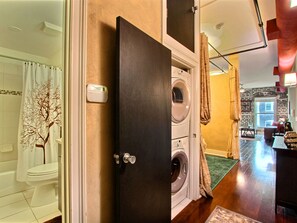 A laundry room with a washing machine and dryer, a white toilet, and a tree-patterned shower curtain. - Heated Pool Access | 5*Clean | Flex Cancelation (Savannah)