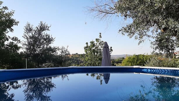 A clear view of a swimming pool surrounded by trees and a distant view of a town. - Country house with a pool in the Alentejo (Arraiolos)