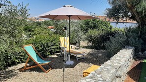 A patio with a pool, a lounge chair, a striped chair, and a stone wall. - Country house with a pool in the Alentejo (Arraiolos)