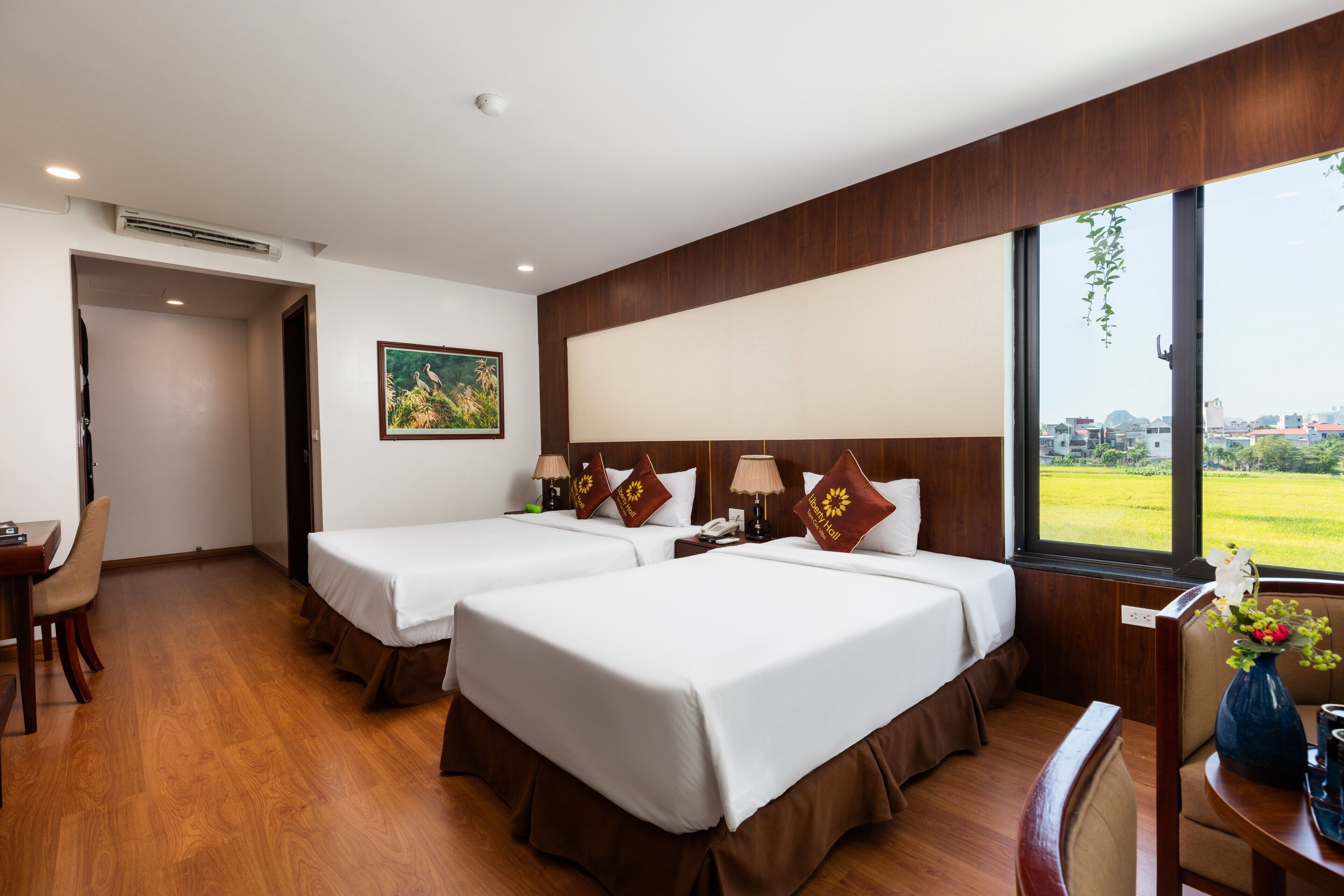 Une chambre d’hôtel avec deux lits, un bureau et une chaise. Il y a une fenêtre donnant sur l’extérieur.