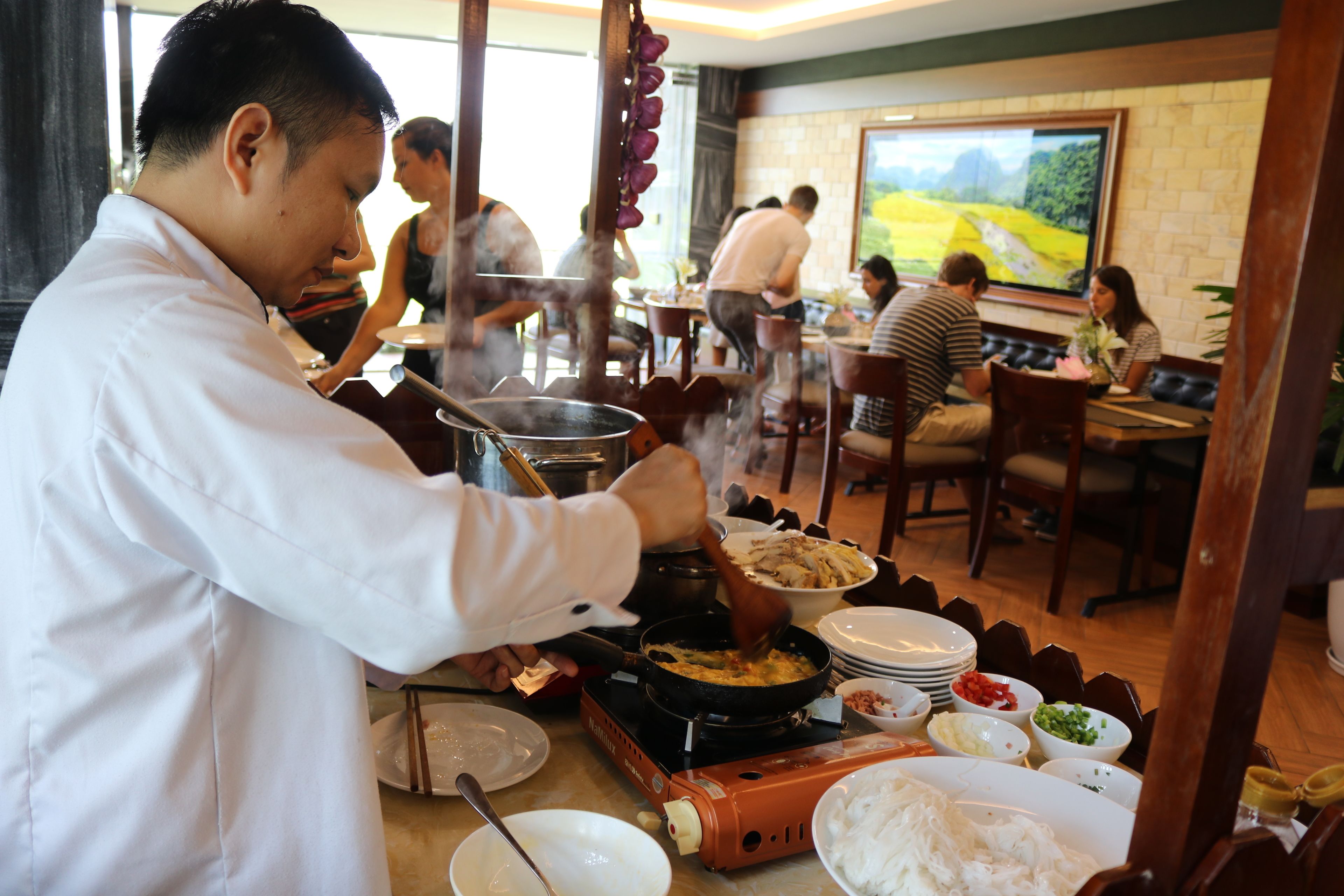 Uno chef cucina in un ristorante con vista su un paesaggio pittoresco.