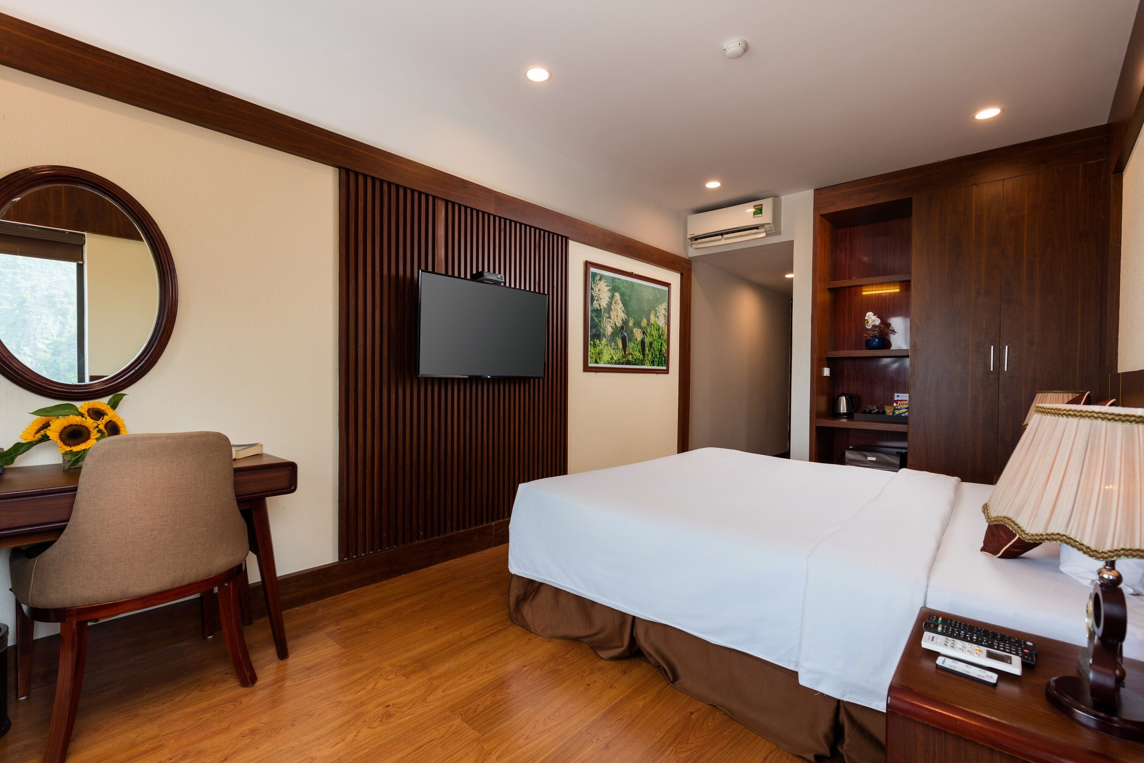 A hotel room with a bed, a desk with a chair, a television, and a wardrobe.