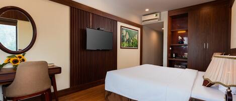 A hotel room with a bed, a desk with a chair, a television, and a wardrobe.