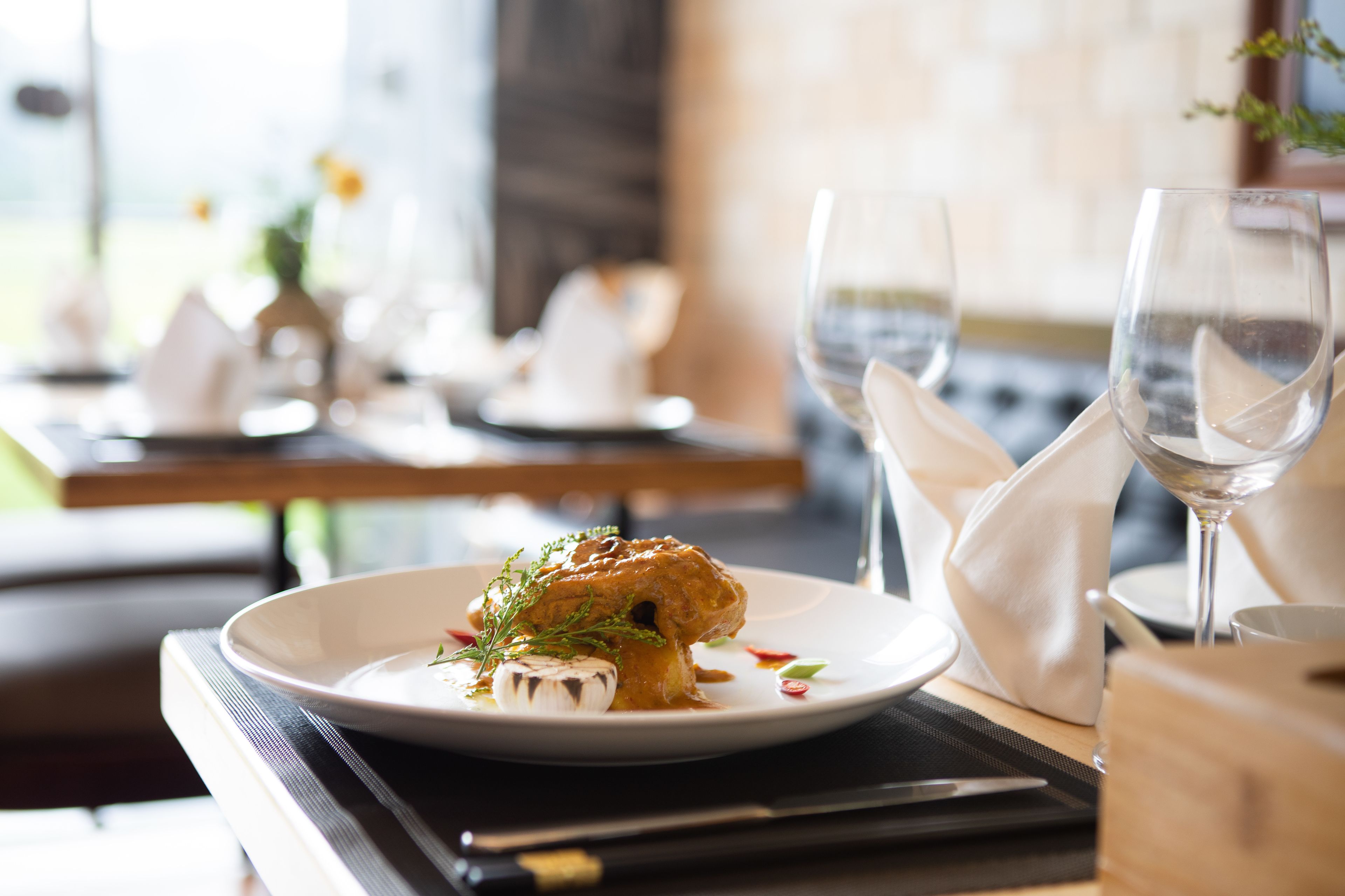 Una mesa de comedor con un plato de comida, una copa de vino y una servilleta.