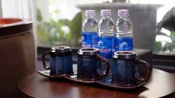 A tray with three dark blue ceramic mugs on a wooden table, with water bottles in the background.