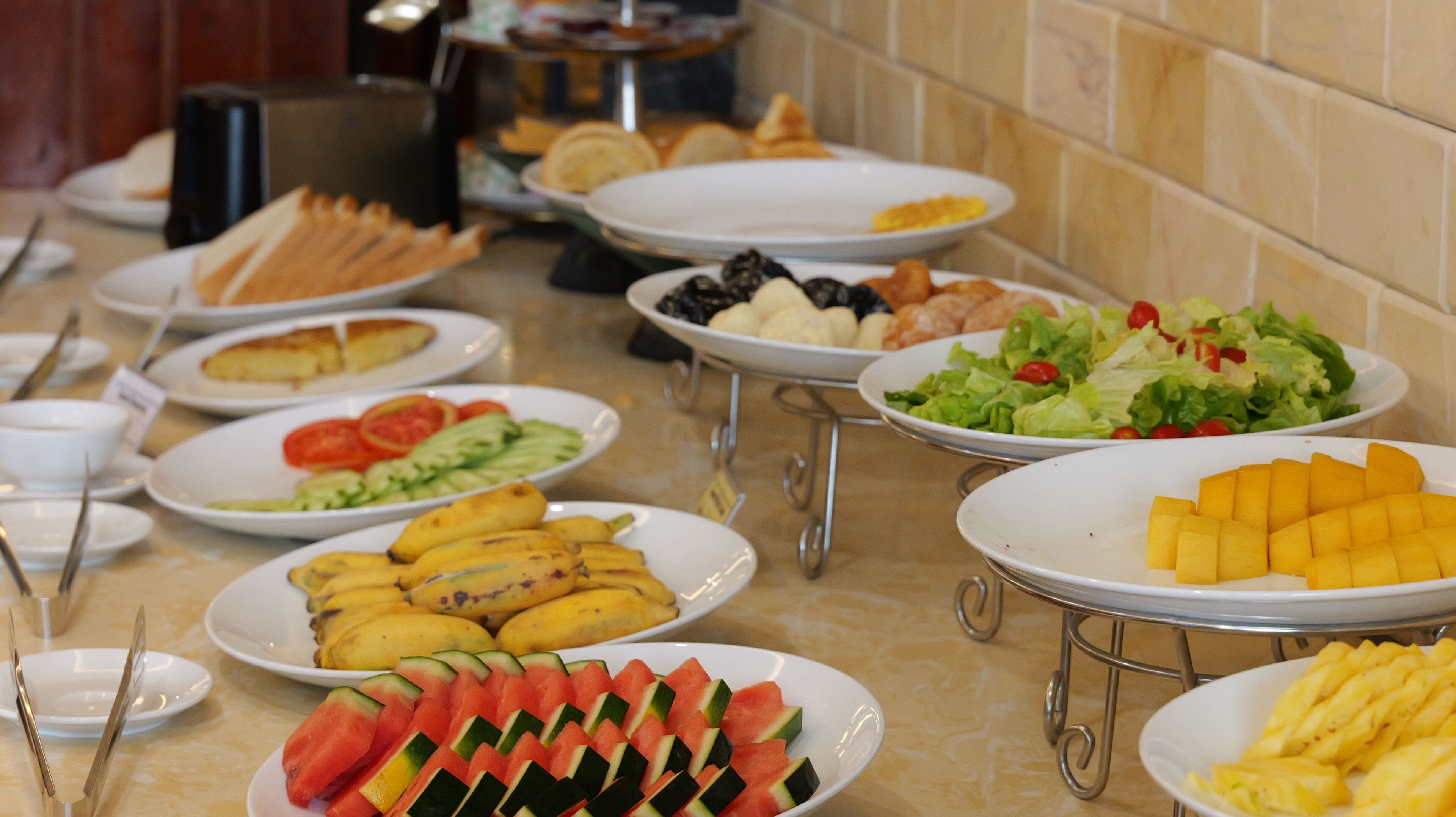 Una mesa de buffet con diversos alimentos, incluyendo frutas, verduras y pan.