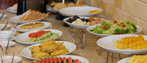 Una mesa de buffet con diversos alimentos, incluyendo frutas, verduras y pan.