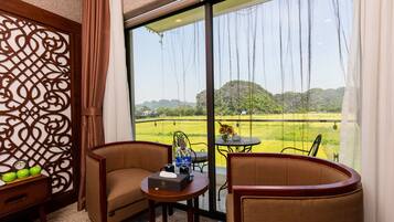 A room with a large window, a wooden chair, a small table, and a decorative screen.