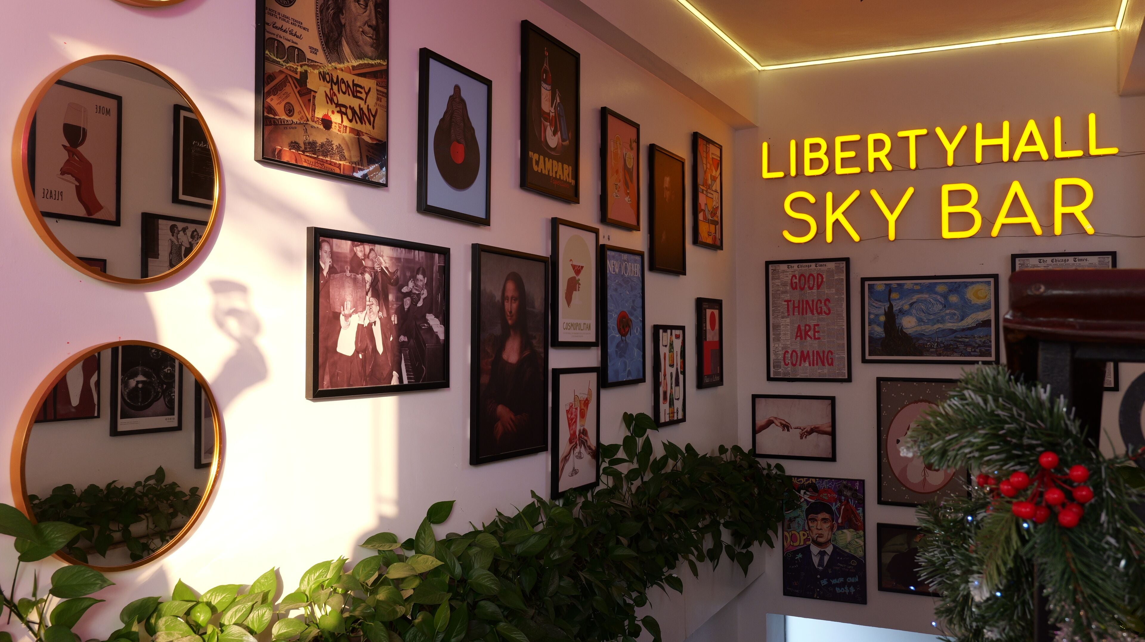 A wall with various framed artworks and a neon sign reading "LIBERTYHALL SKY BAR".