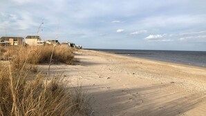 A sandy beach with houses along the shore and a clear sky.