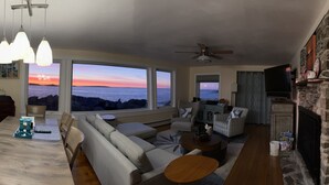 Amplia sala de estar con una gran mesa de comedor, asientos y una chimenea de piedra.