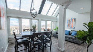 A dining area with a table and chairs, a chandelier, and large windows offering a view of the landscape. - #1 Rare 4Br Lux True Ski in Out @5 lifts Pool/Spas/Gym/WD/FP/Parking Near Main! (Park City)
