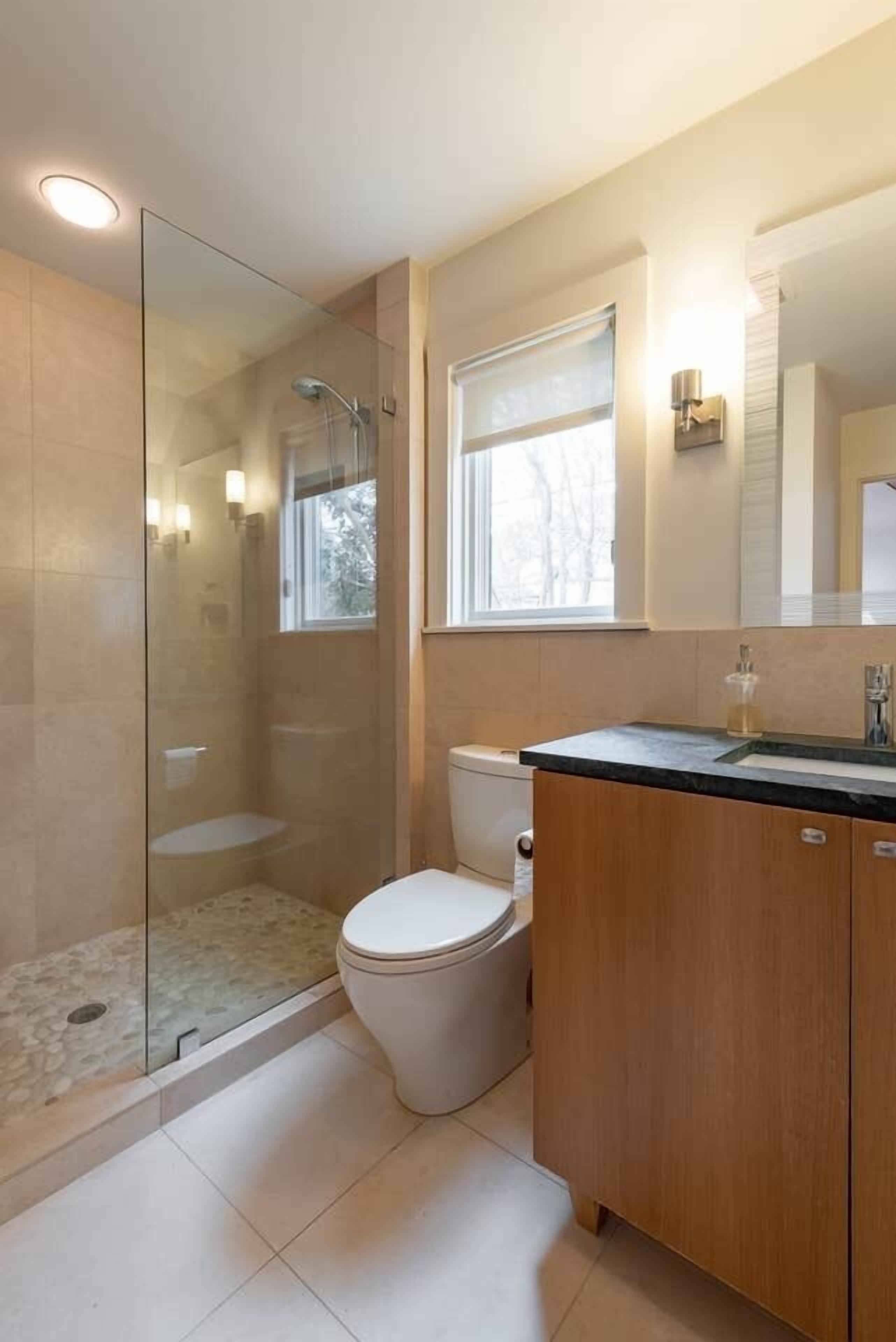 Ein modernes Badezimmer mit einer Duschkabine, einer Toilette und einem Waschtisch mit Spiegel.