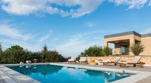 A swimming pool with lounge chairs and a modern building in the background. - Villa Mariposa- Panoramic Sea View - Near Chania City - Private Pool - Spacious  (chania)