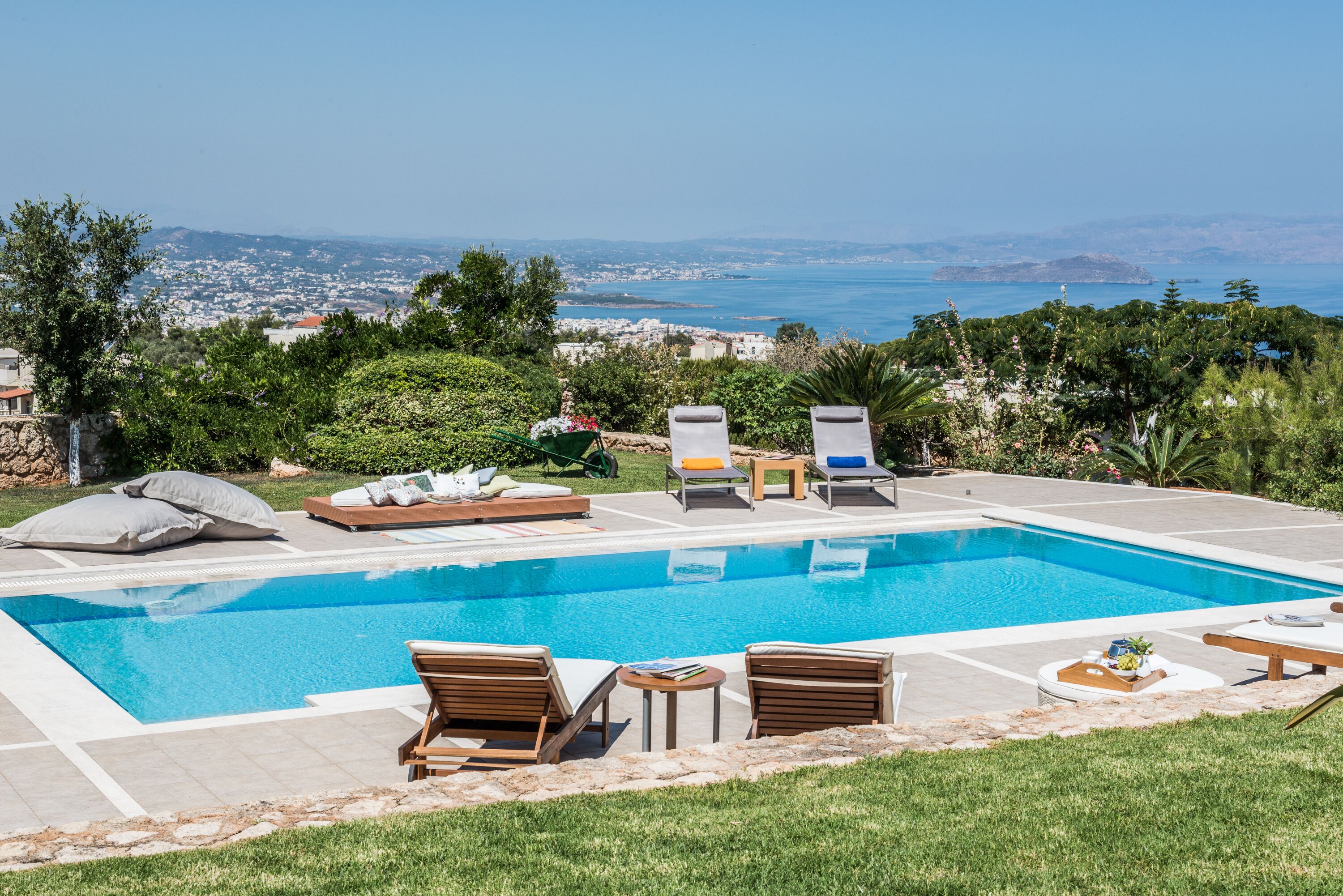A swimming pool with lounge chairs and a view of the city and sea.