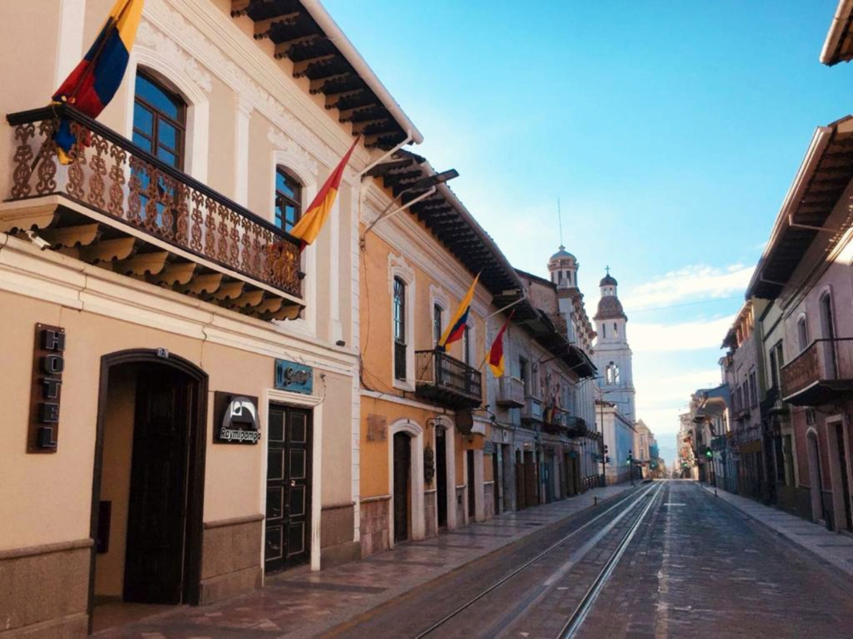 Rua com edifícios, um hotel chamado 'Hotel Raymipampa' e uma igreja ao fundo.
