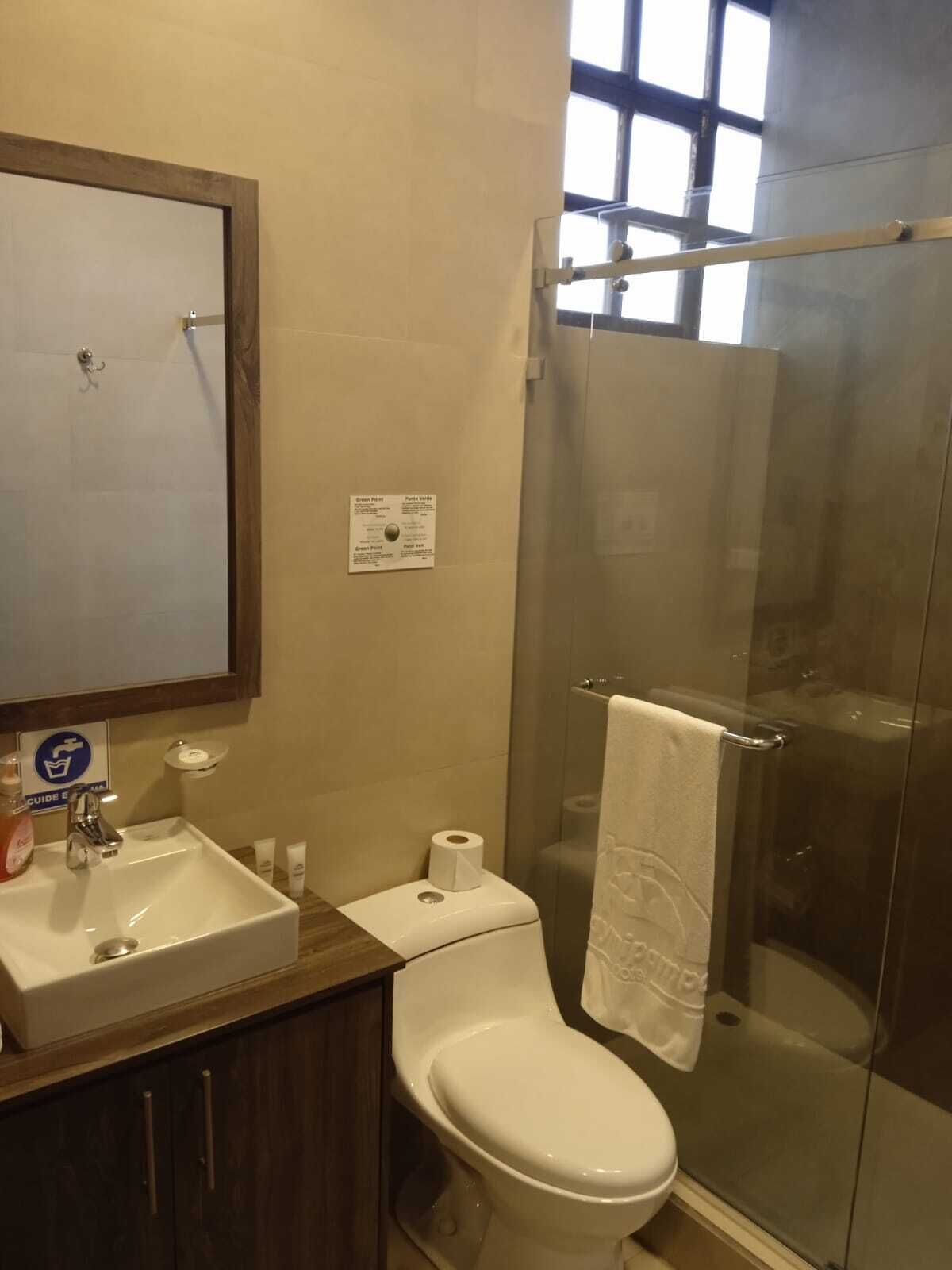 Un baño con lavamanos, inodoro y cabina de ducha de vidrio.