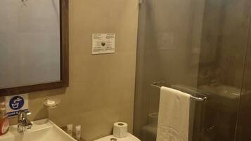 Un baño con lavamanos, inodoro y cabina de ducha de vidrio.