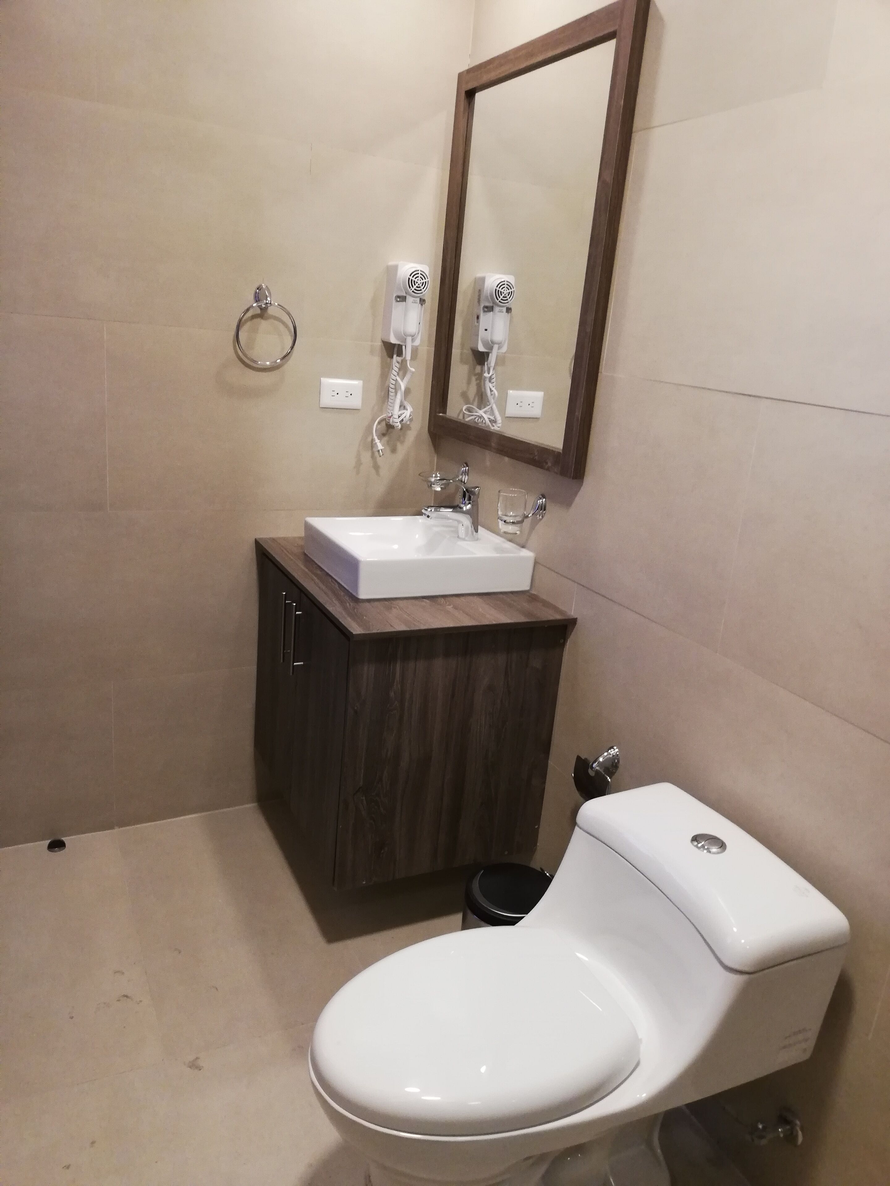 A bathroom with a white sink, a wooden cabinet, a mirror, and a toilet.