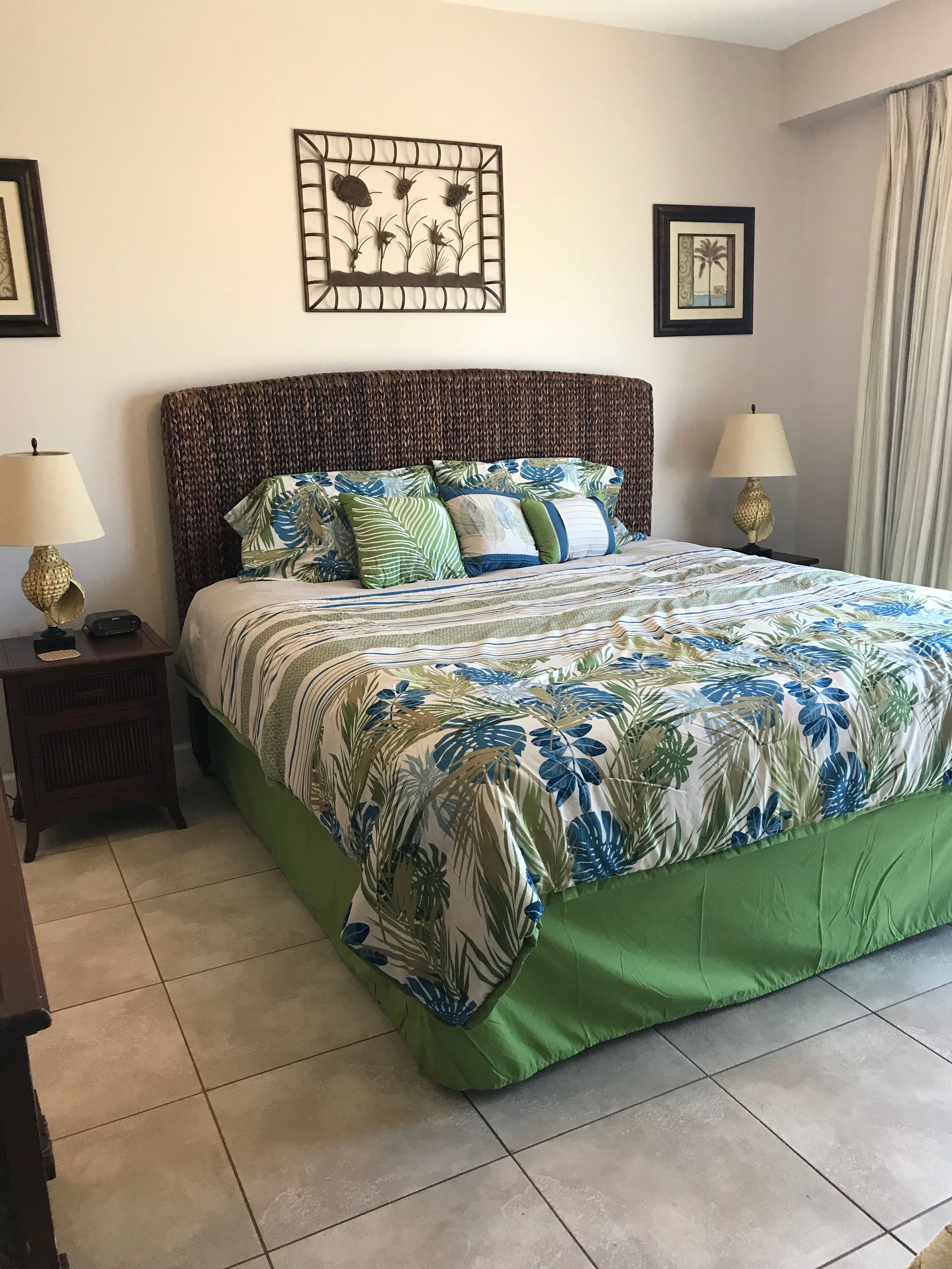 A neatly made bed with a floral bedspread, two bedside tables with lamps, and framed artwork on the walls.