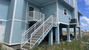A two-story house with a balcony and a covered outdoor seating area. - Beach Front/First Row on the Gulf of Mexico, next to the Dune Crossover. 2B/2B (Pensacola Beach)