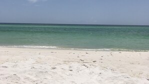 A beach with clear turquoise water and a white sandy shore. - Beach Front/First Row on the Gulf of Mexico, next to the Dune Crossover. 2B/2B (Pensacola Beach)