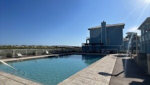 A clear blue sky, a swimming pool, and a building with a flat roof and large windows. - Beach Front/First Row on the Gulf of Mexico, next to the Dune Crossover. 2B/2B (Pensacola Beach)