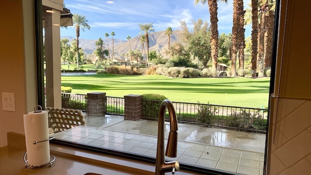 A bathroom with a large window overlooking a golf course, a toilet paper holder, and a faucet. - Beautifully Renovated 2/2 in Monterey CC with Mountain Views (Palm Desert)