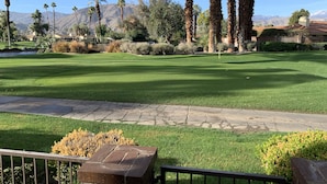 A well-maintained lawn with a stone pathway, palm trees, and a mountain backdrop. - Beautifully Renovated 2/2 in Monterey CC with Mountain Views (Palm Desert)