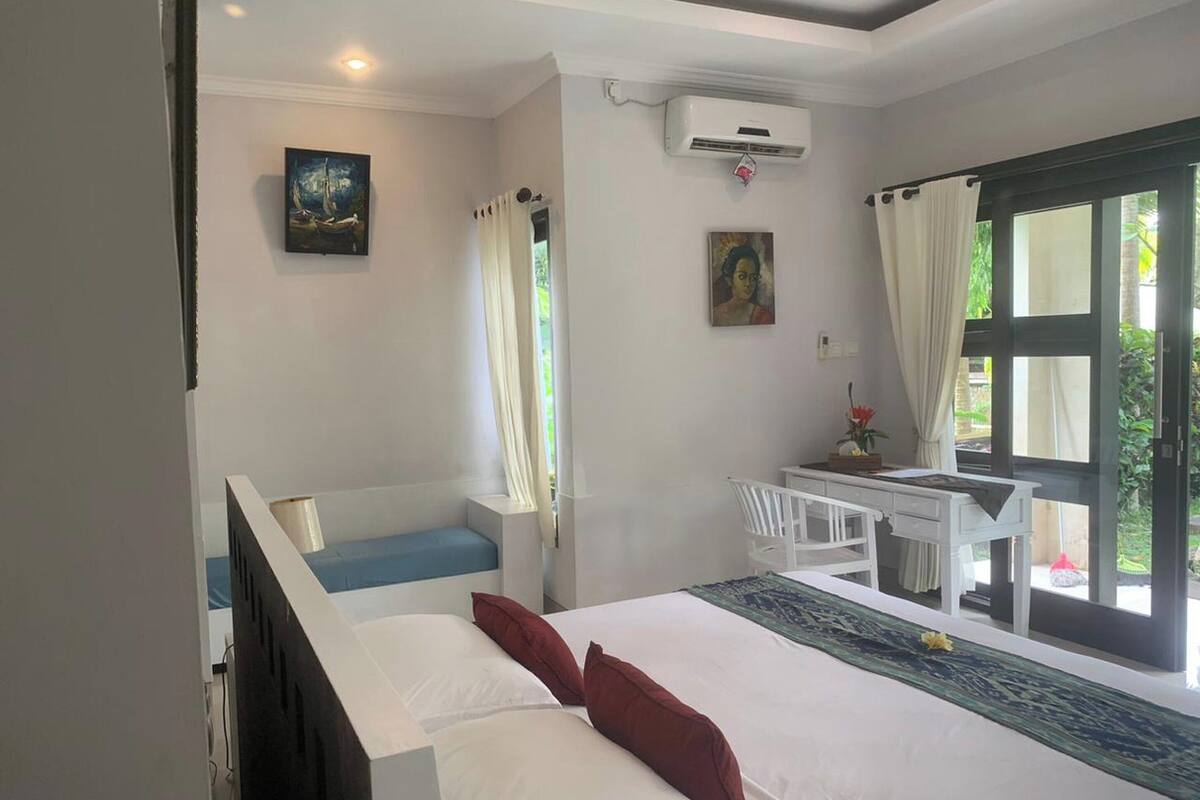 Un dormitorio con cama, escritorio y ventana.