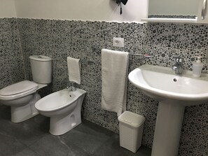A bathroom with a toilet, bidet, sink, and a trash bin. - Al Chiaro di Luna (Taormina)